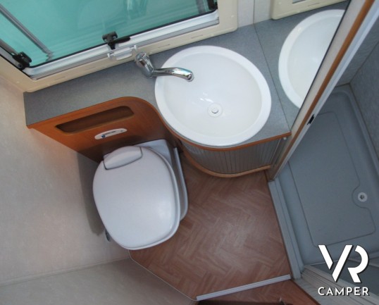 Adria Coral 630: camper mansardato usato con letti a castello posteriori, bagno con doccia separata e dinette classica.