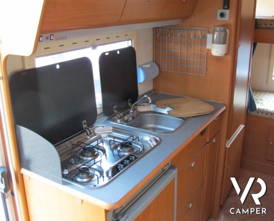 Adria Coral 630: camper mansardato usato con letti a castello posteriori, bagno con doccia separata e dinette classica.