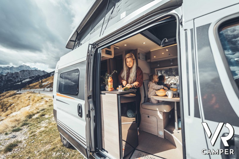 famiglia pranza su camper furgonato con portellone aperto