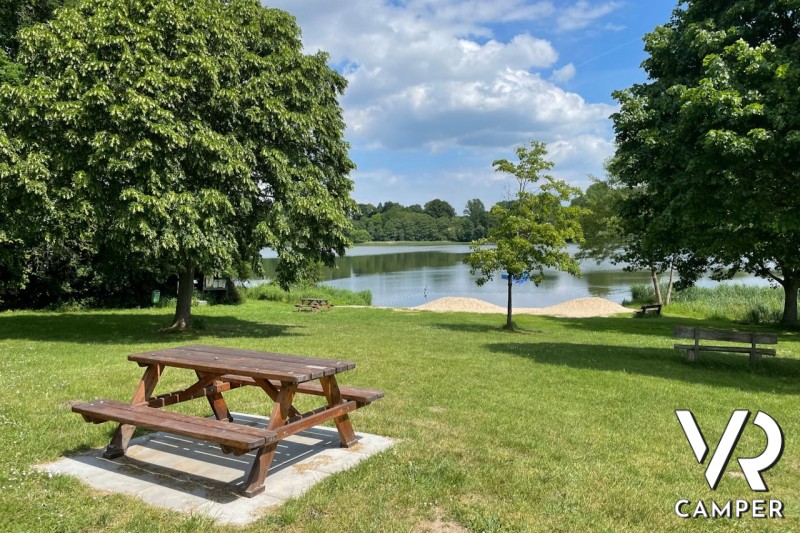 area picnic con tavoli di legno su prato vicino ad un laghetto