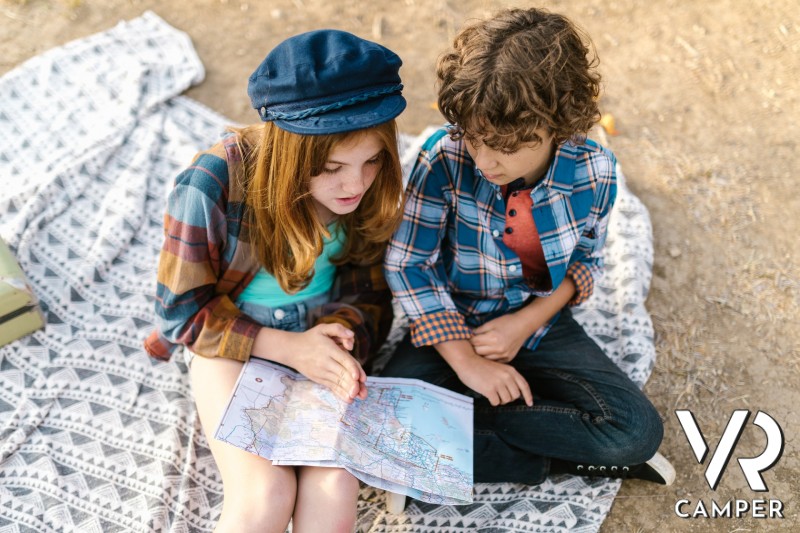 bambini con cartina stradale, seduti su coperta da picnic