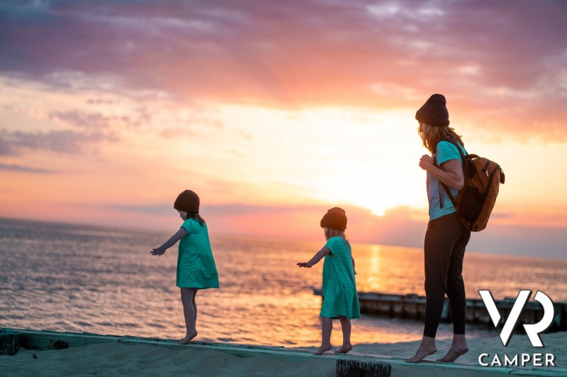 mamma con due bimbe in riva al mare al tramonto