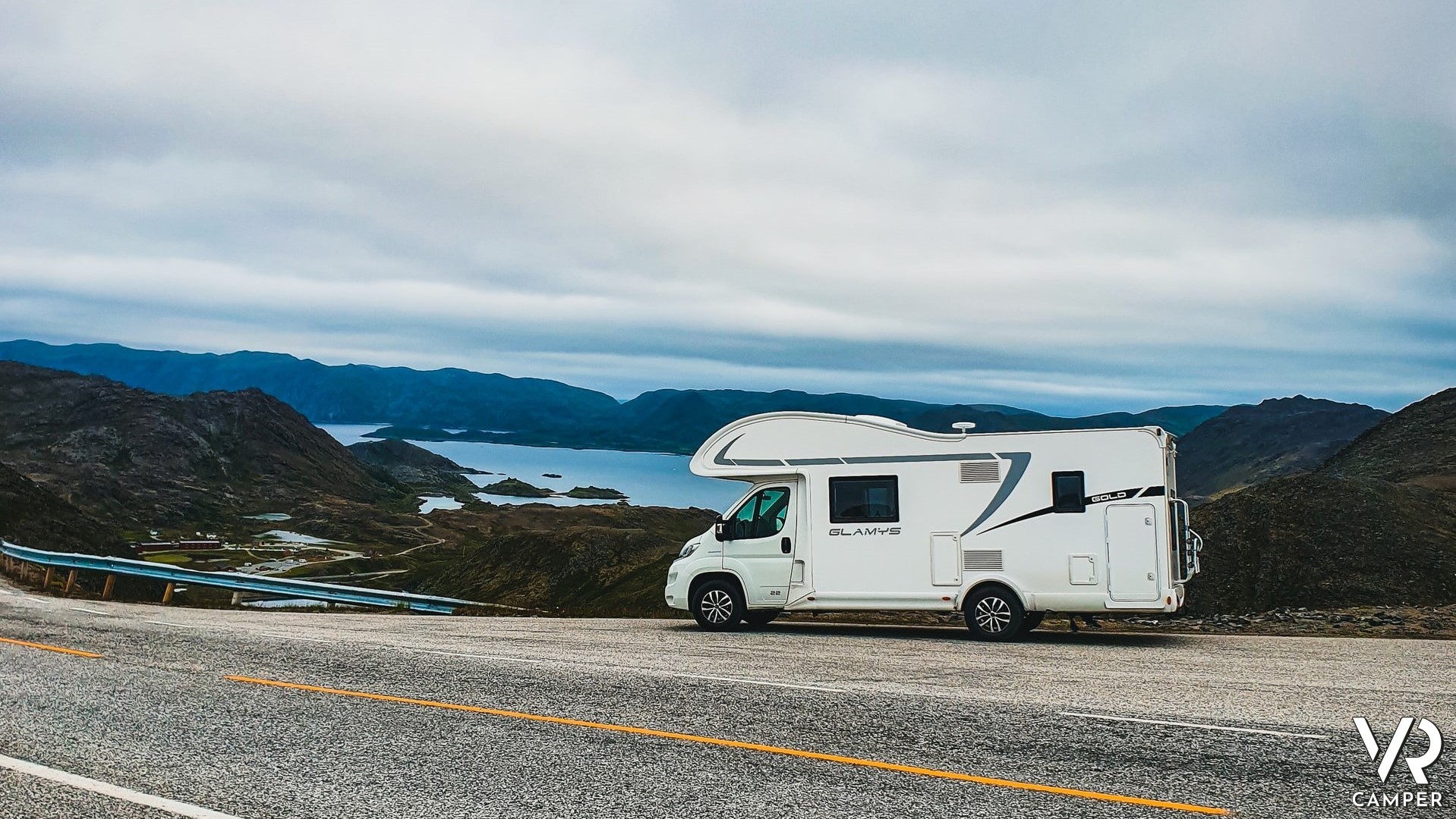 Camper in viaggio su strada che costeggia un lago - Meglio acquistare un camper nuovo o un camper usato?