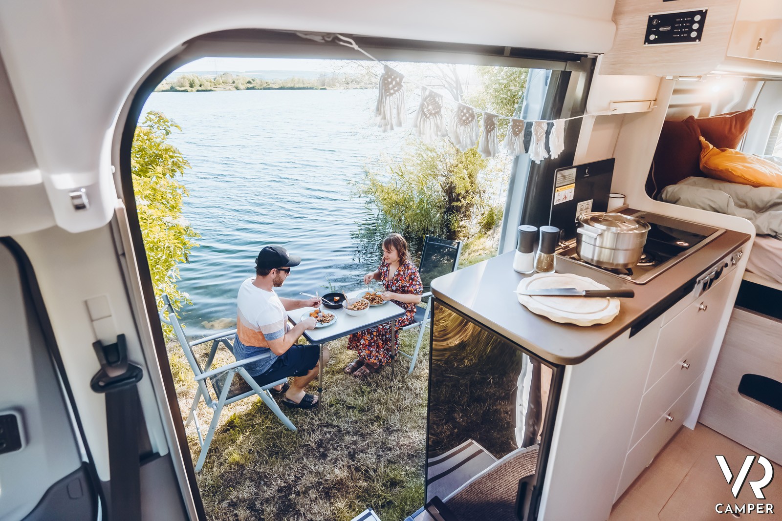 Coppia fa colazione sul tavolino, vista dall'interno del camper