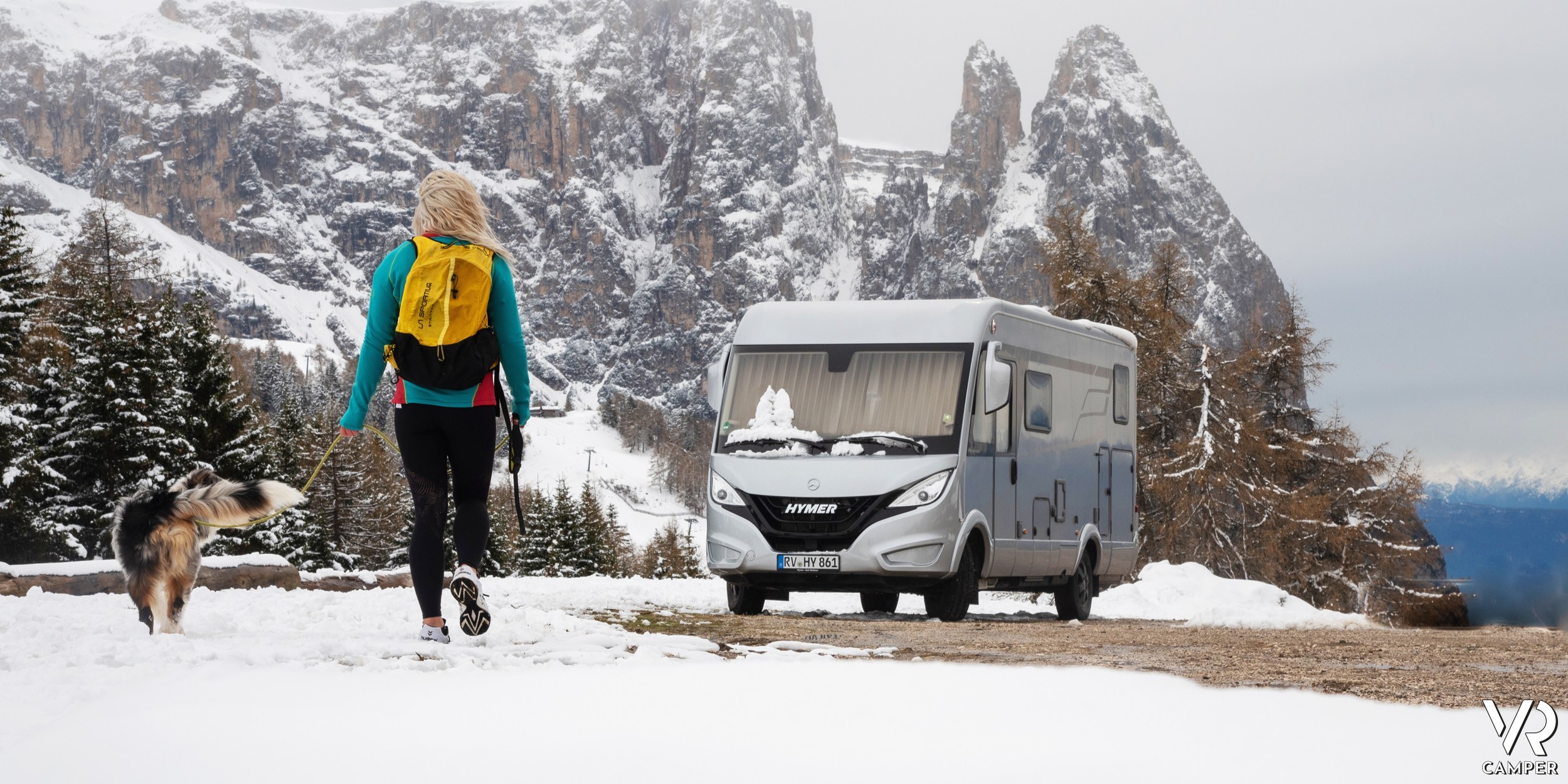 camper motorhome in montagna tra la neve, con donna e cane